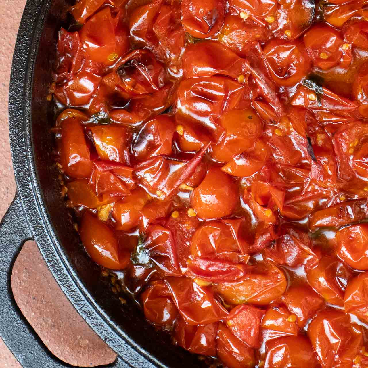 jammy roasted tomatoes with extra virgin olive oil in cast iron skillet