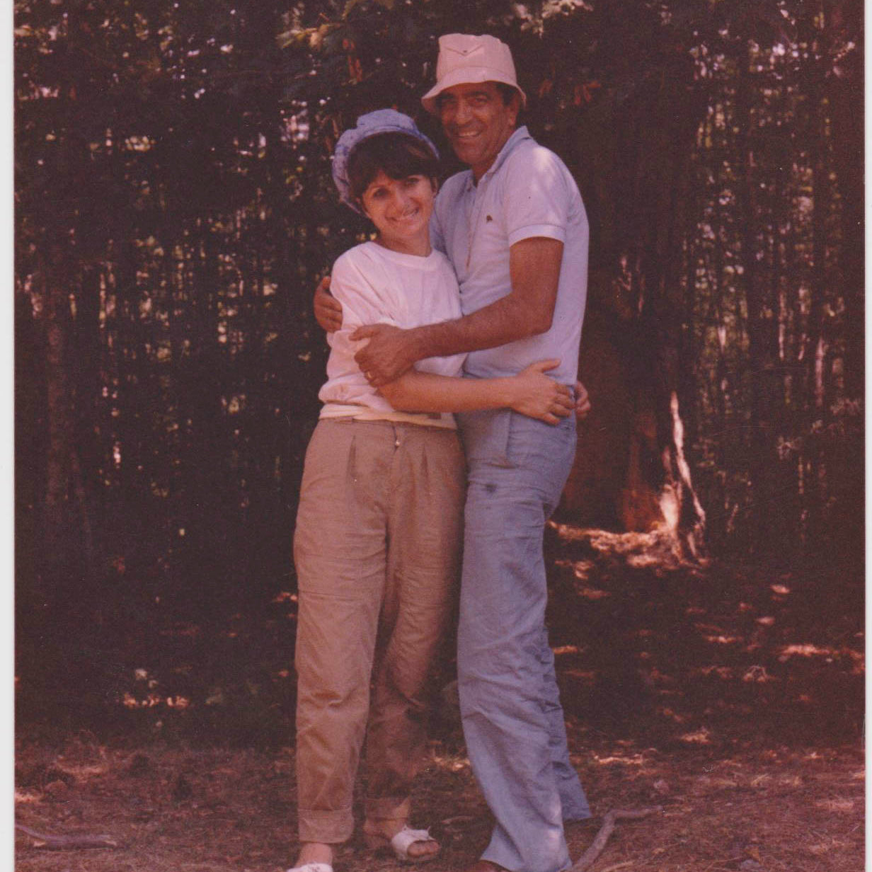 Slightly faded color photo of an Italian husband and wife, Salvatore and Lina, smiling and embracing in a forest in Calabria Italy while on vacation