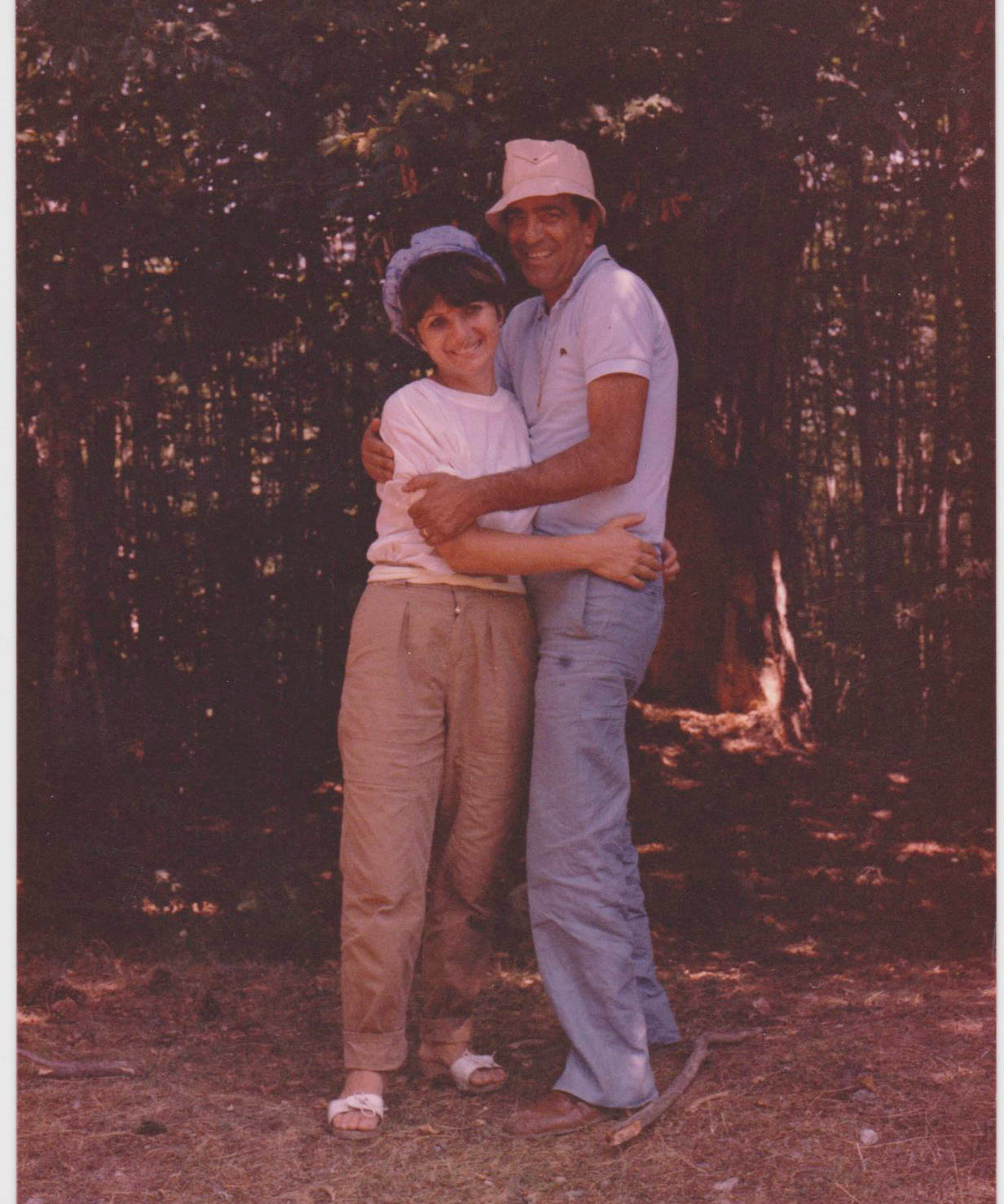 Slightly faded color photo of an Italian husband and wife, Salvatore and Lina, smiling and embracing in a forest in Calabria Italy while on vacation